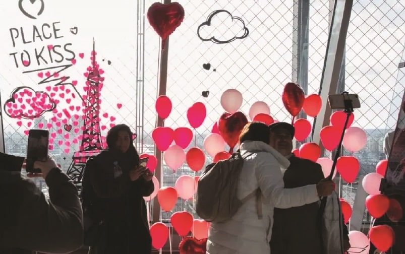 Un couple s’embrassant devant une décoration romantique avec des ballons et des cœurs à Paris, évoquant l’idée d’un lieu parfait et intime, tout comme notre expertise pour dénicher des biens d’exception à Paris