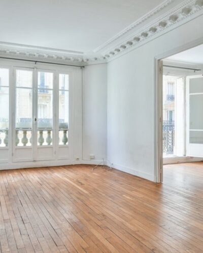 Salon lumineux d’un appartement 3 pièces de charme avec balcon, situé dans le quartier Lamarck-Caulaincourt à Paris 18e.