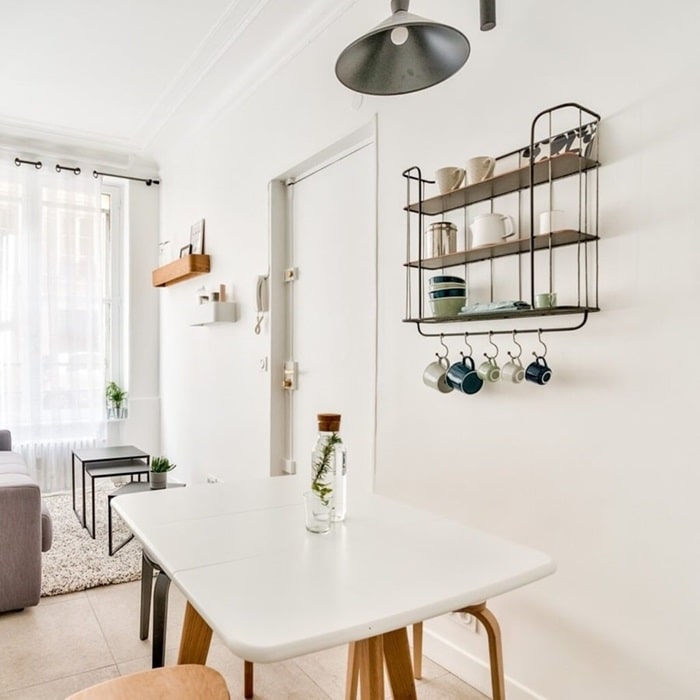 Salle à manger lumineuse et décorée avec une table blanche, étagères murales et déco minimaliste, située dans un deux-pièces de la rue d'Aumale, quartier Nouvelle Athènes, Paris 9e.