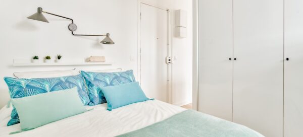 Chambre moderne et lumineuse avec literie aux tons bleus et grands rangements, dans un appartement deux pièces situé à Asnières, à proximité du métro, présenté par un chasseur d'appartement dans les Hauts-de-Seine.