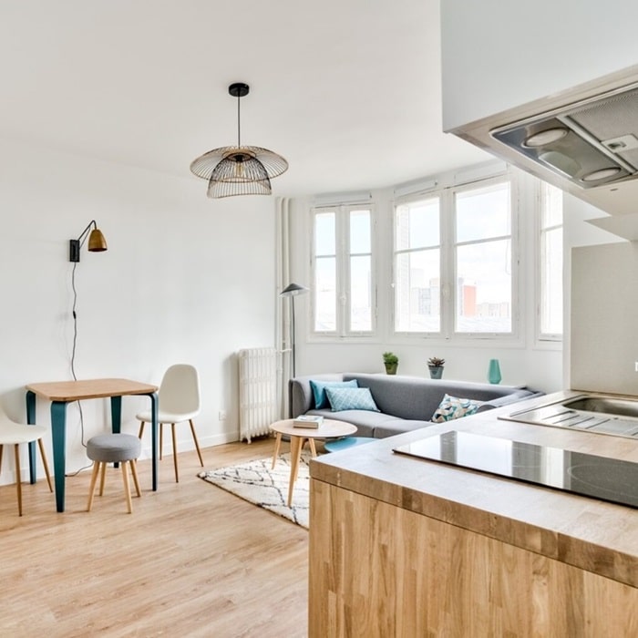 Une cuisine ouverte moderne et fonctionnelle donnant sur un espace repas convivial dans un appartement d'Asnières-sur-Seine