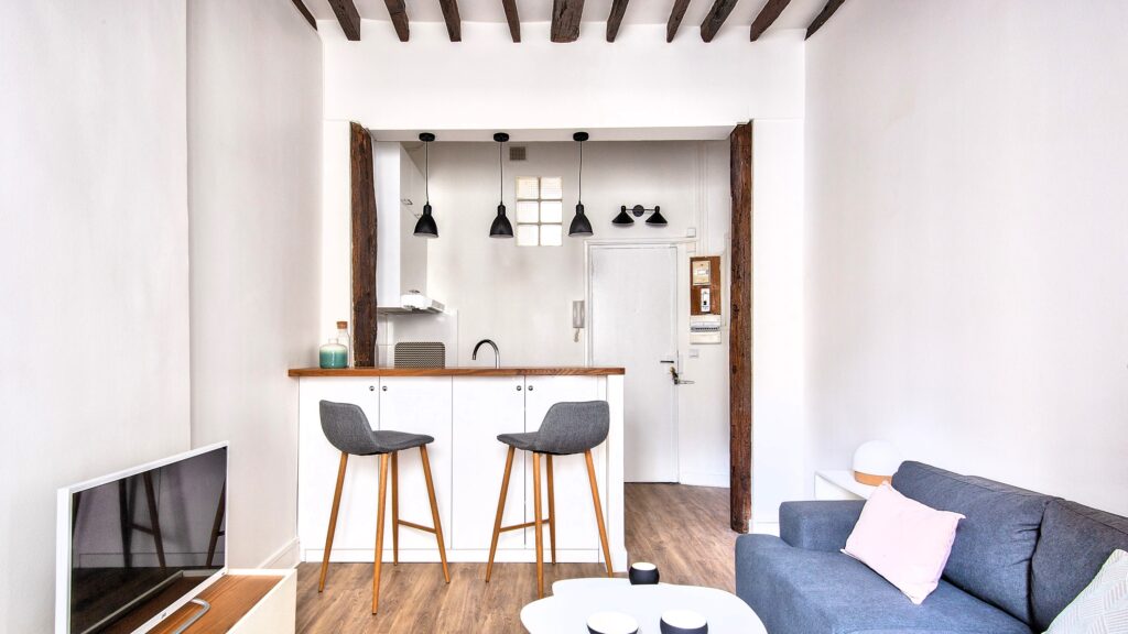 Studio haut de gamme rénové avec poutres apparentes, cuisine ouverte et espace salon moderne dans le 9e arrondissement de Paris.