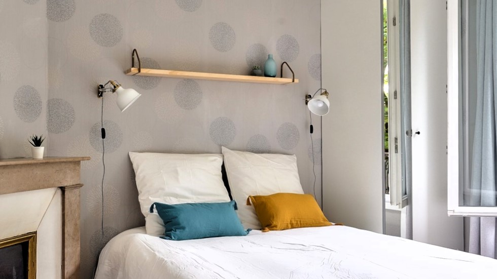 Chambre lumineuse et chaleureuse avec cheminée décorative et lit double, située à Neuilly-sur-Seine.