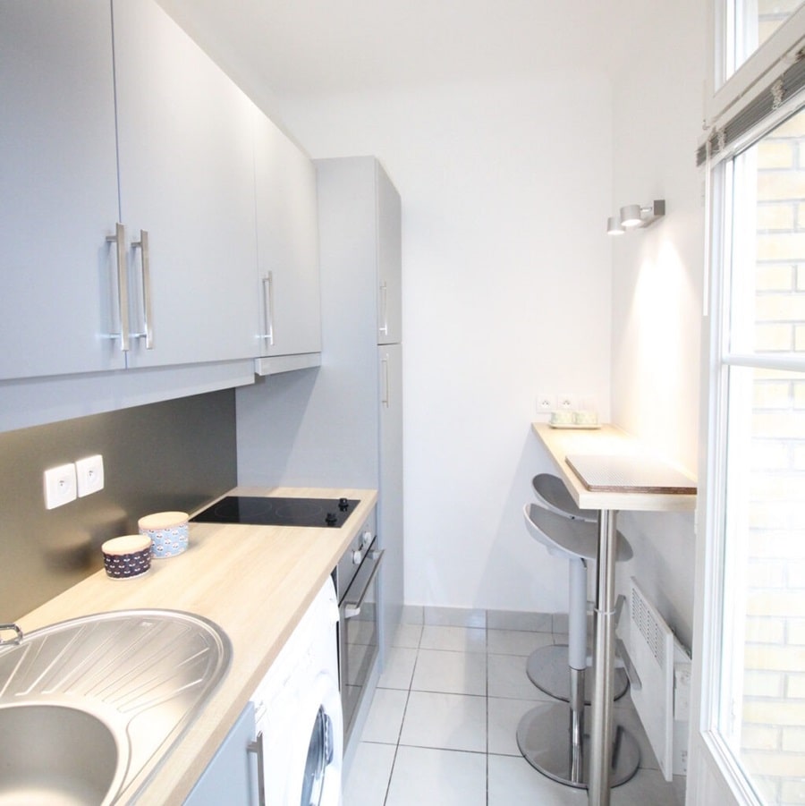 Petite cuisine fonctionnelle et lumineuse dans un appartement à Clichy, équipée de rangements modernes et d’un coin repas, idéale pour un investissement locatif.