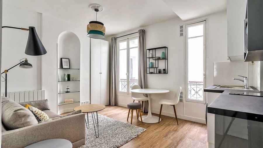 Vue intérieure d'un appartement rénové à Auteuil, Paris 16e, combinant un salon, une salle à manger et une cuisine moderne dans un espace optimisé.