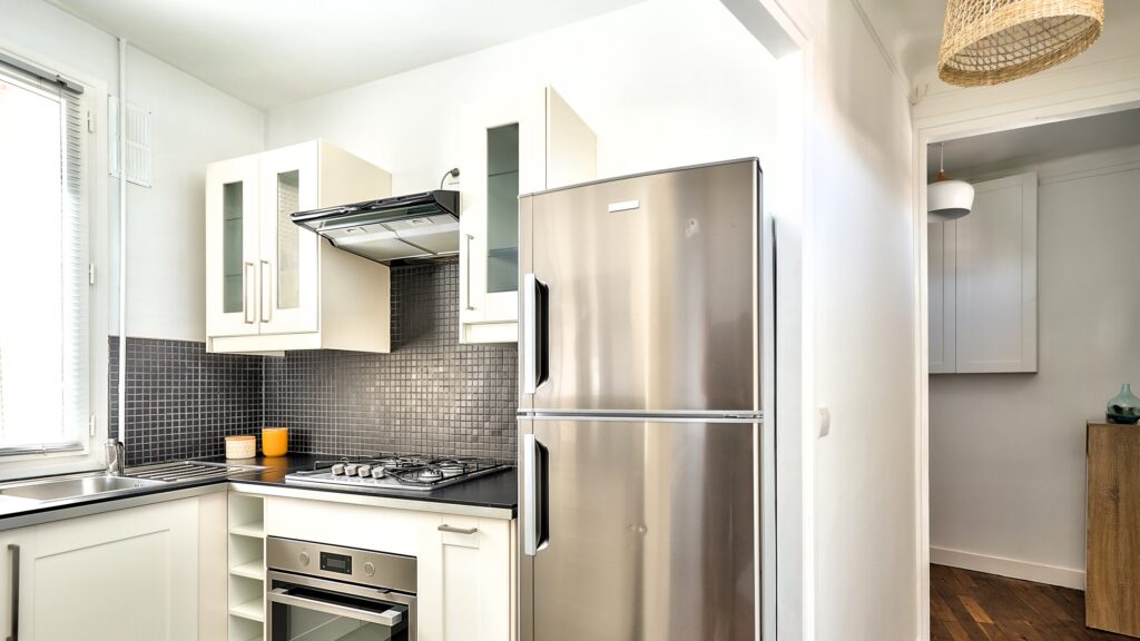 Cuisine fonctionnelle avec électroménagers modernes, façades blanches et crédence en mosaïque, sélectionnée par Early Birds, chasseurs immobiliers à Paris et ses environs, dans un appartement Rue Sébastopol à La Garenne-Colombes.