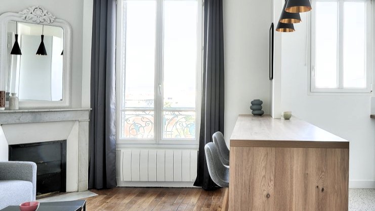 Salon lumineux d'un appartement rénové à Bois-Colombes, avec une cheminée décorative et une grande fenêtre offrant une belle vue.