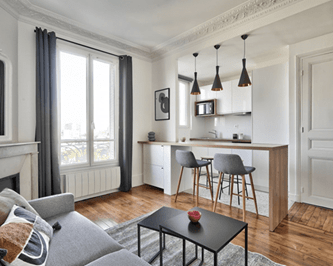 Appartement parisien rénové avec cuisine ouverte, parquet en bois, et décoration moderne, conçu pour la location courte durée ou Airbnb, combinant confort et style pour les voyageurs.