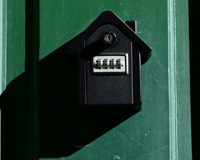 Boîte à clés murale noire installée sur une porte verte, idéale pour gérer l'accès des locataires dans des locaux commerciaux adaptés à la location courte durée à Paris, type Airbnb