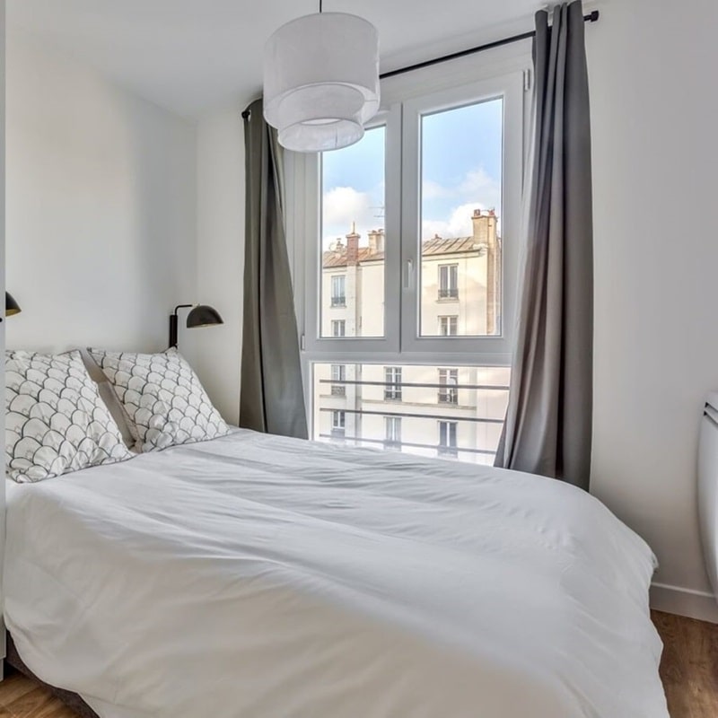 Chambre lumineuse dans un appartement à Clichy (92), conçue par Early Birds avec une décoration minimaliste et une vue sur les toits parisiens