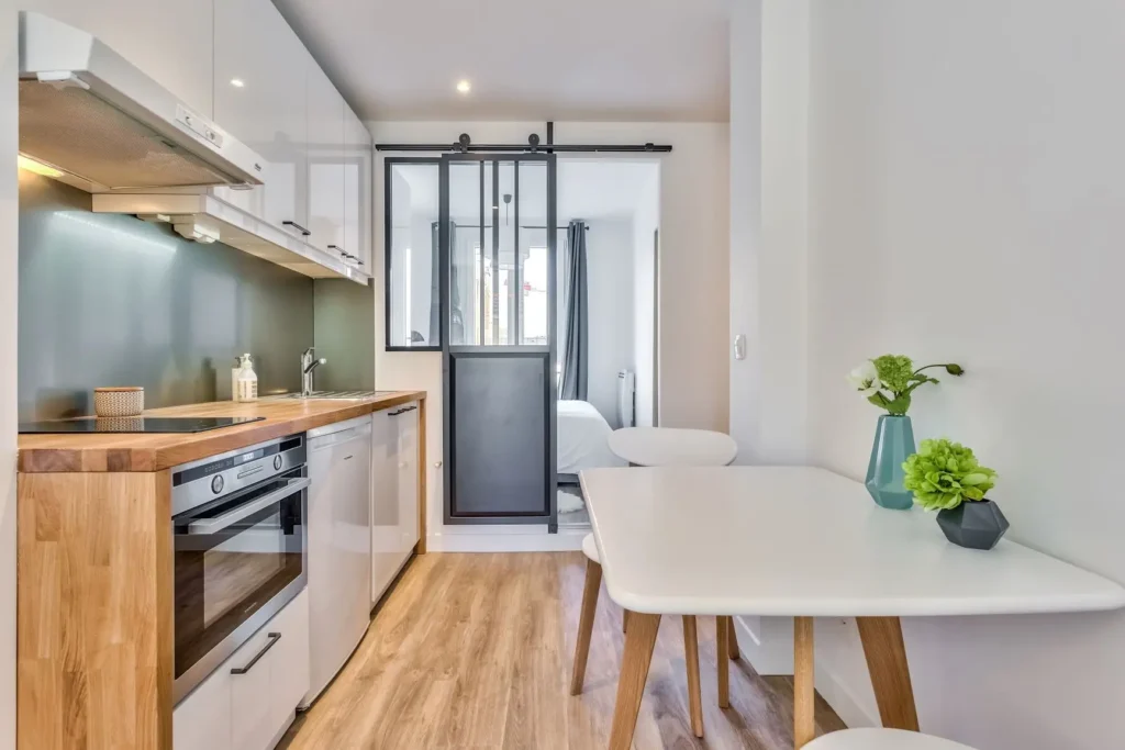Cuisine et coin repas dans un appartement à Clichy (92), réalisé par Early Birds, avec une verrière moderne et un design fonctionnel et épuré.