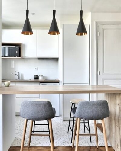 Cuisine ouverte moderne avec îlot central en bois et luminaires design dans un appartement rénové à Bois-Colombes (92), proche de la gare.