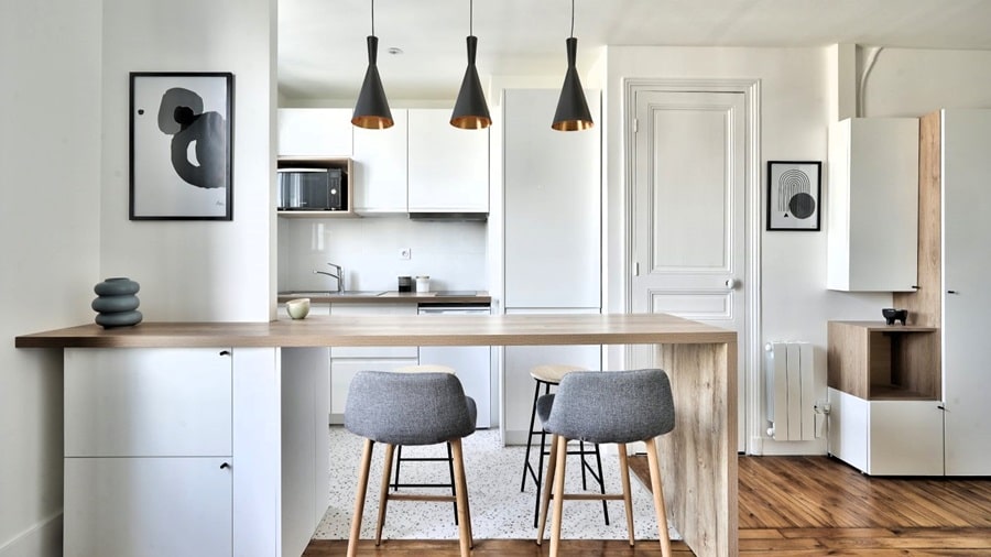 Cuisine ouverte moderne avec îlot central en bois et luminaires design dans un appartement rénové à Bois-Colombes (92), proche de la gare.