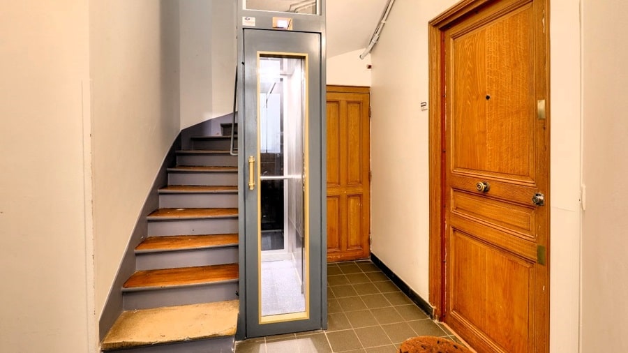 Palier d’immeuble parisien avec un ascenseur moderne et une porte en bois, situé dans le 12e arrondissement de Paris.