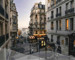 Vue d'une rue typiquement parisienne avec immeubles haussmanniens et commerces, soulignant le potentiel touristique et commercial pour l'achat de locaux adaptés à la location courte durée type Airbnb