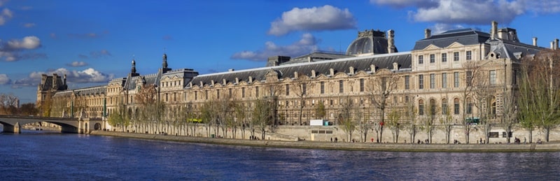 Vue panoramique du musée du Louvre et de la Seine, emblématique du 1er arrondissement de Paris, un lieu prisé pour des projets immobiliers prestigieux avec Early Birds Paris.