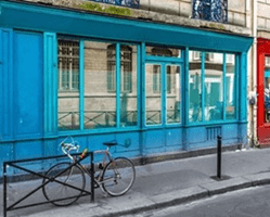Façade colorée d'un local commercial parisien avec de grandes vitrines, idéalement situé pour un projet de location courte durée ou Airbnb, combinant visibilité et accessibilité dans un quartier vivant
