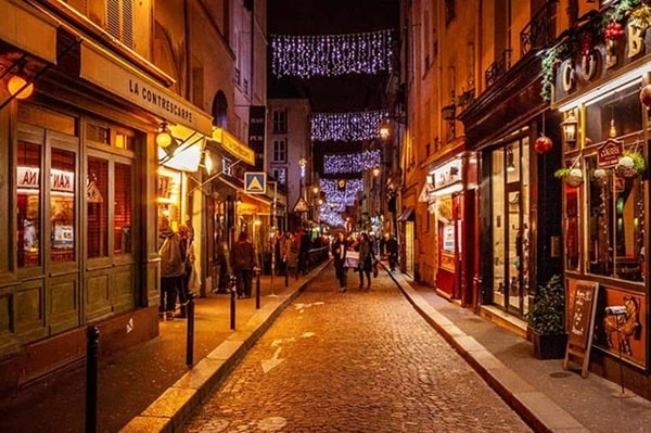 Vue nocturne de la rue Mouffetard illuminée, près de la place de la Contrescarpe, dans le 5ᵉ arrondissement de Paris.