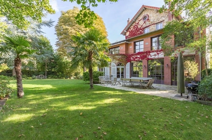 Maison en première couronne de Paris avec grand jardin arboré, façade ancienne et espaces extérieurs, illustrant un cadre résidentiel verdoyant hors Paris intra-muros.
