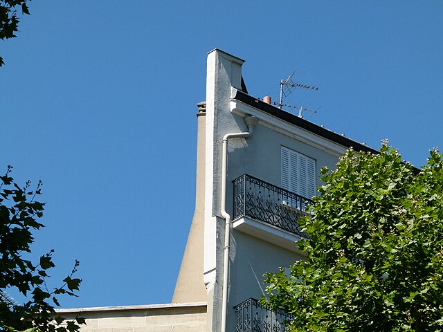 Dernier étage d’un immeuble parisien ancien vu de l’extérieur, façade étroite et toiture visible