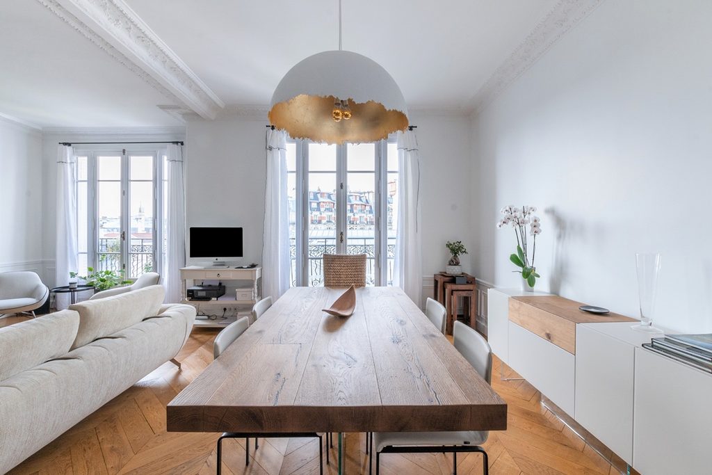 Séjour lumineux d’un appartement parisien avec parquet et moulures